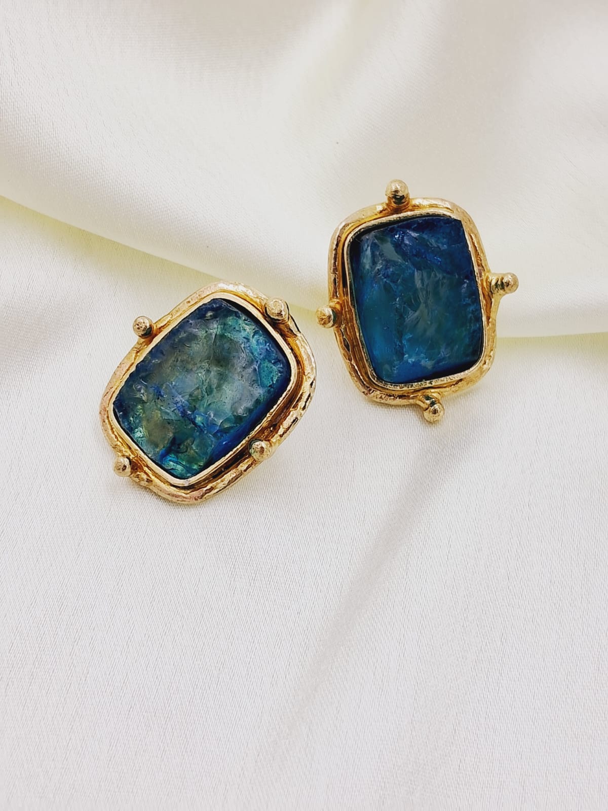 This stud is made from Rough blue  Crystal semi precious stone stud surrounded by gold plating giving a square look alike shape.