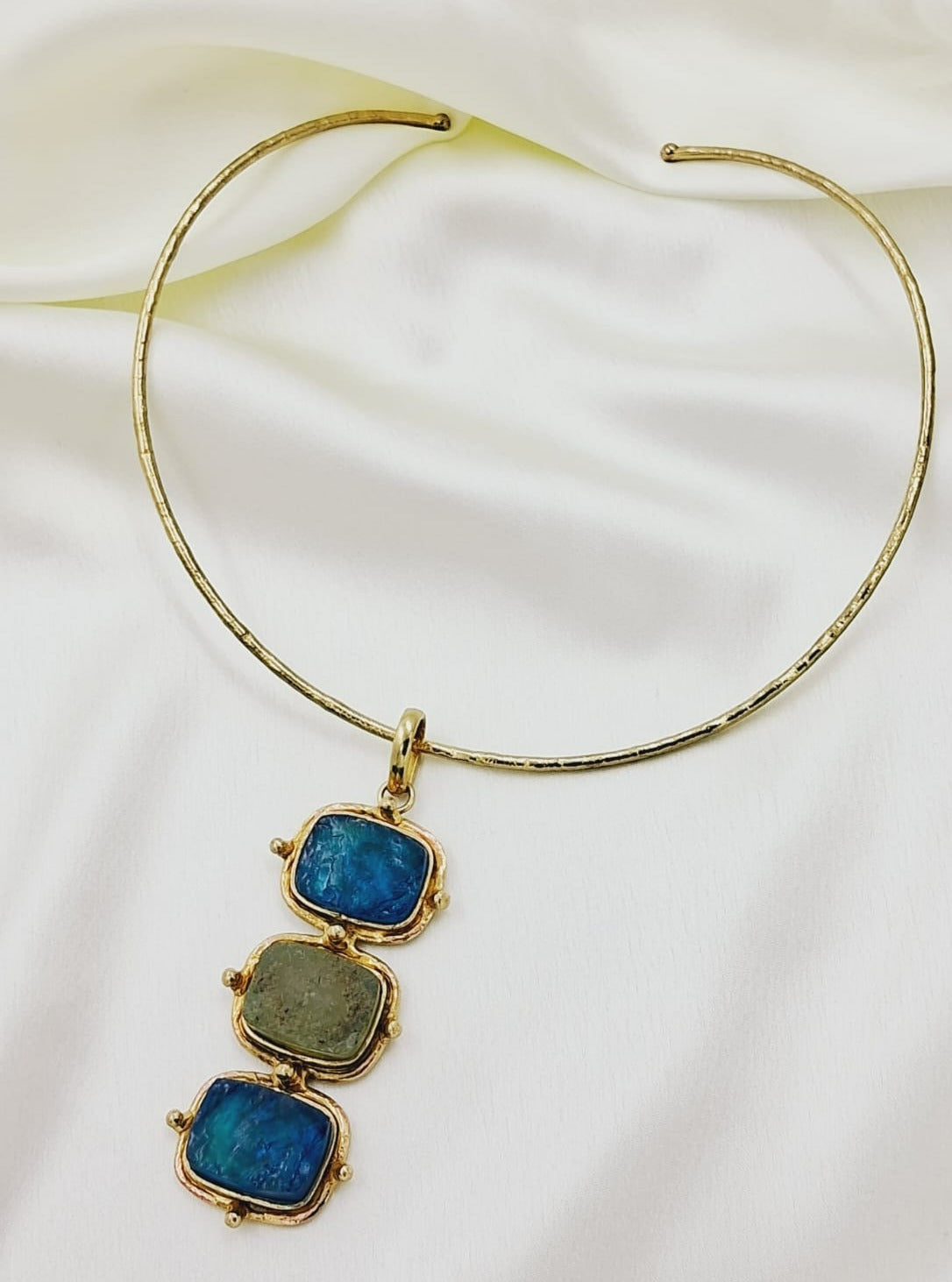 This necklace is made by rough blue three square look alikse semi precious stone hanging by gold plated adjustable hasli.